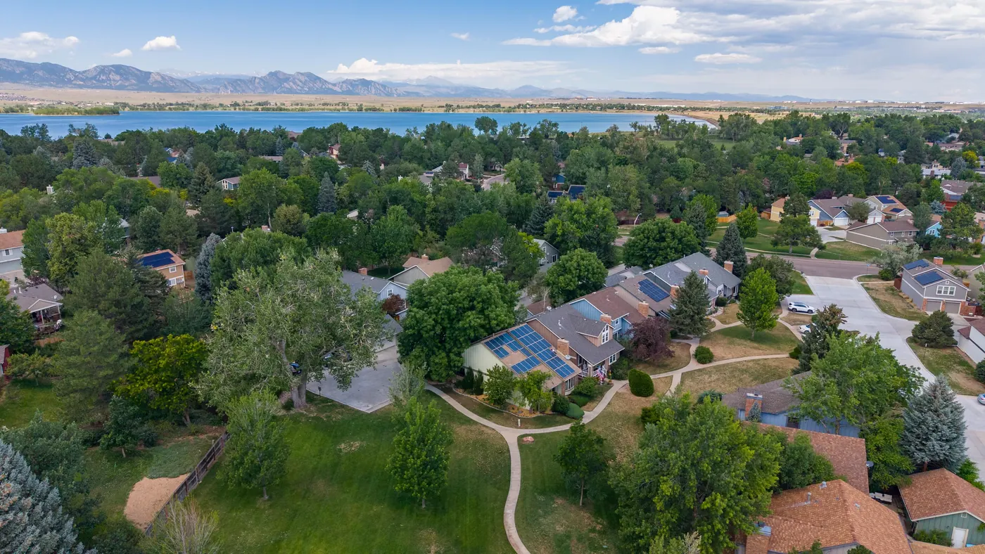 The home under mature trees with Standley Lake in the distance