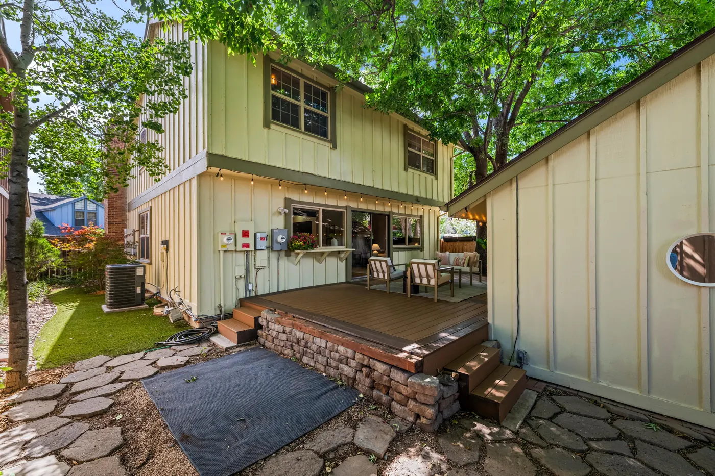 Back of the home with deck steps down to a flagstone patio