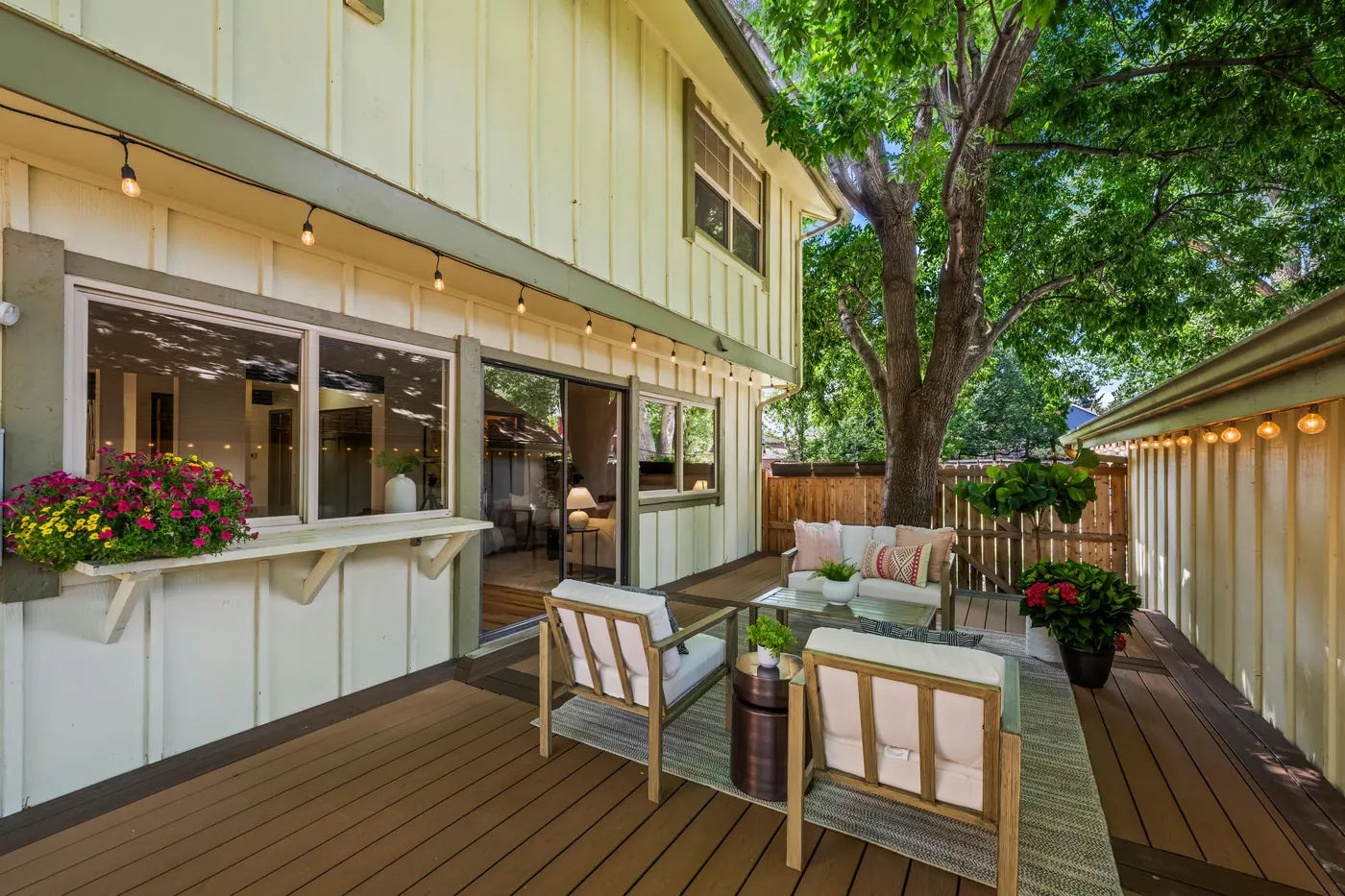 Trex deck with twinkle lights strung overhead and a seating area in the shaded backyard