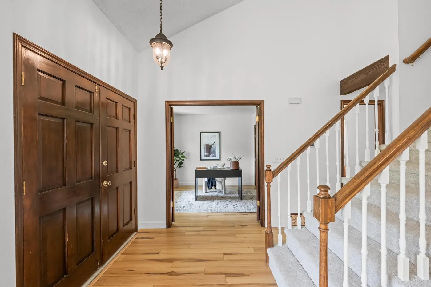 Vaulted foyer with double front doors and pendant light