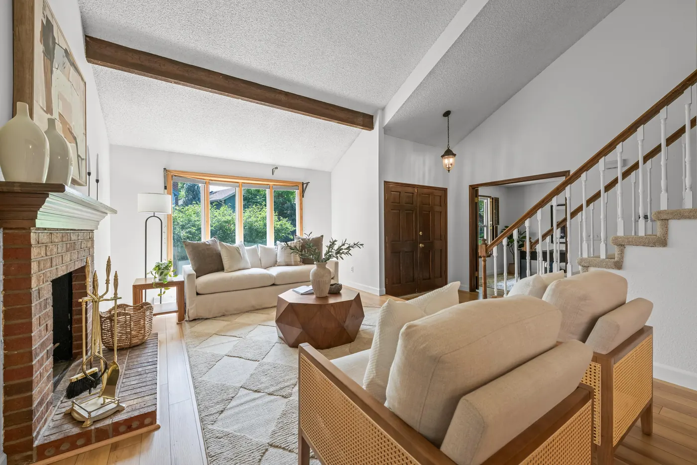 Vaulted living room with exposed beam and oversized window