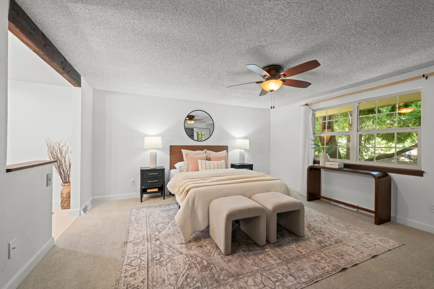 Primary bedroom with ceiling fan and tree-shaded windows